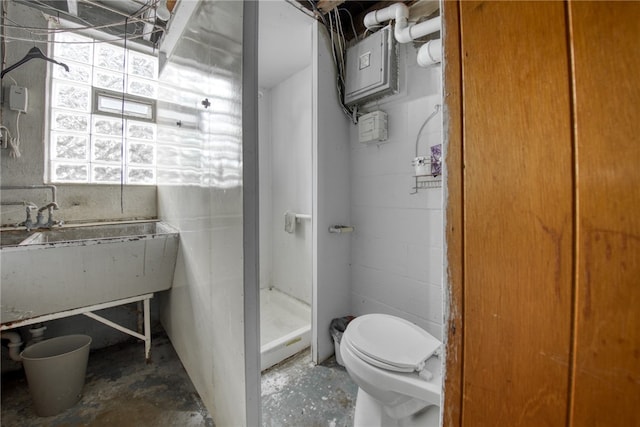 bathroom with a shower, toilet, and concrete flooring