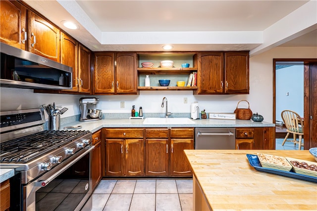 kitchen featuring appliances with stainless steel finishes, light tile patterned flooring, and sink