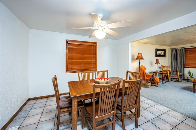 dining area with ceiling fan and light colored carpet