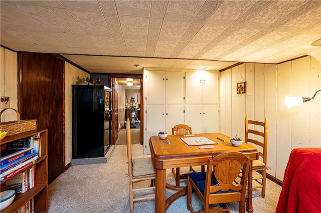 dining room featuring wooden walls and light carpet