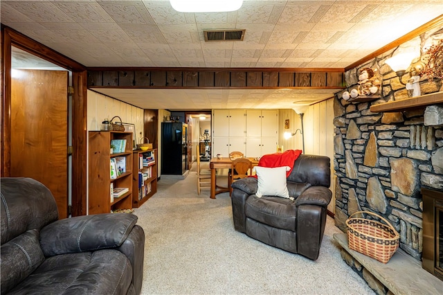 carpeted living room featuring wood walls and a stone fireplace