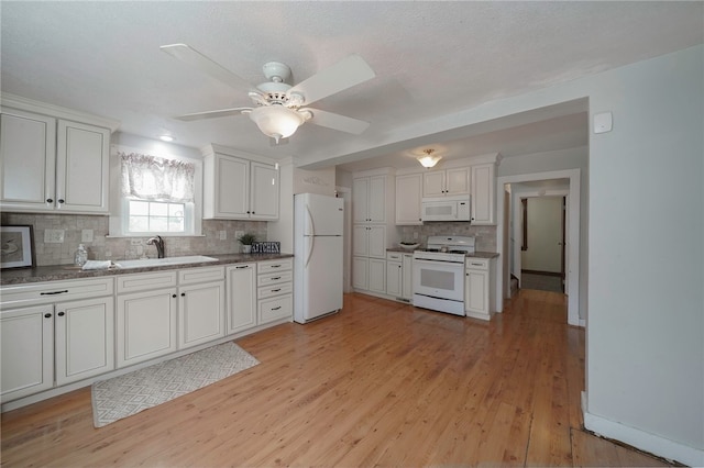 kitchen featuring white appliances, white cabinetry, sink, and ceiling fan