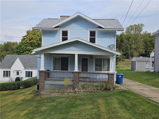 view of front of home with a front yard, covered porch, and an outbuilding