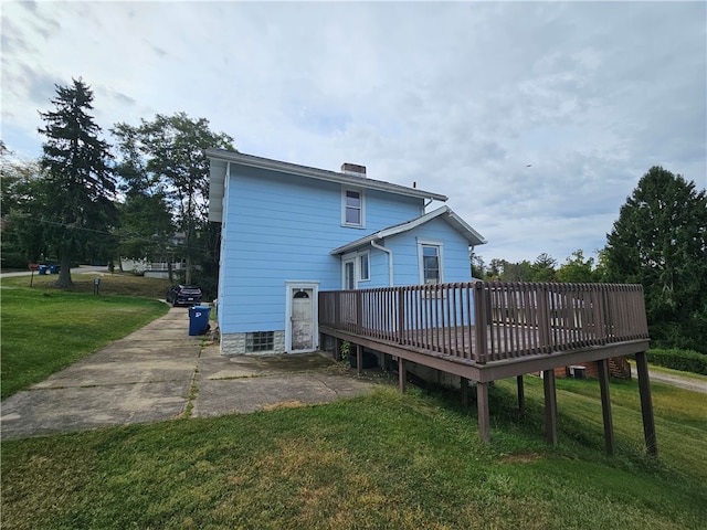 rear view of house featuring a wooden deck and a yard