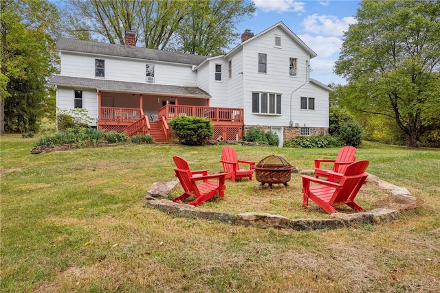 back of house with a fire pit, a deck, and a yard