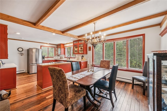 dining area featuring wood-type flooring, a chandelier, a baseboard heating unit, and a healthy amount of sunlight