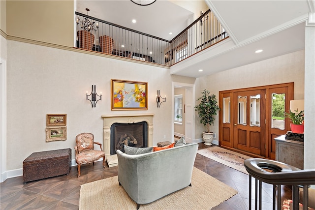 living room featuring crown molding, dark parquet flooring, a towering ceiling, and a fireplace