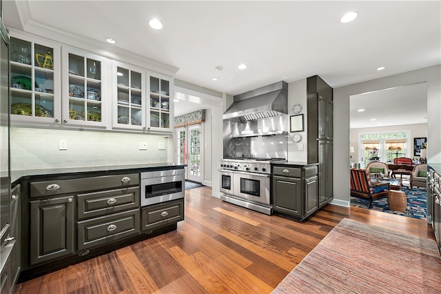 kitchen with appliances with stainless steel finishes, dark hardwood / wood-style floors, tasteful backsplash, and wall chimney range hood