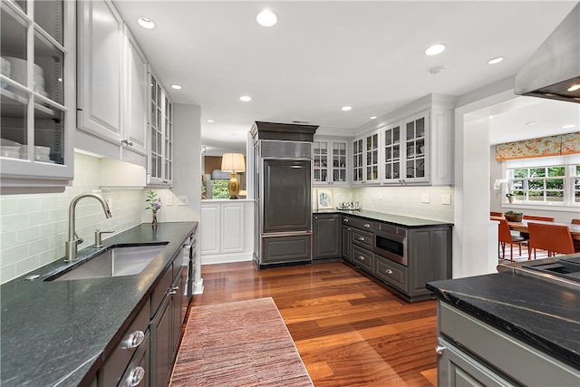 kitchen with dark wood-type flooring, white cabinets, backsplash, stainless steel microwave, and sink