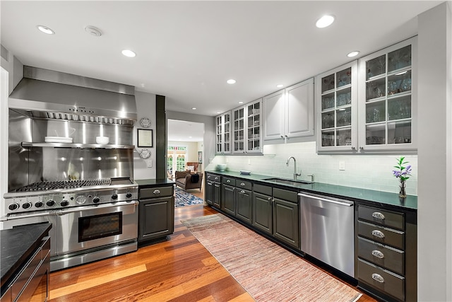 kitchen with light wood-type flooring, tasteful backsplash, sink, white cabinets, and appliances with stainless steel finishes