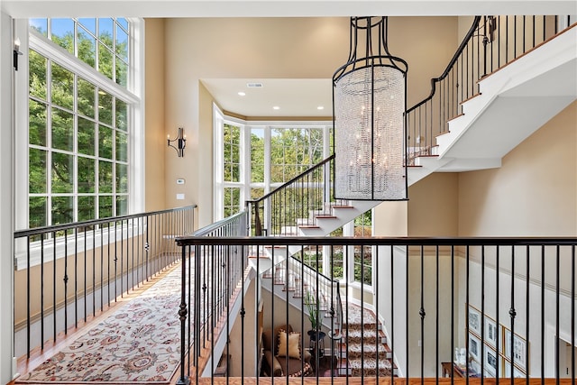 staircase with a notable chandelier and a towering ceiling