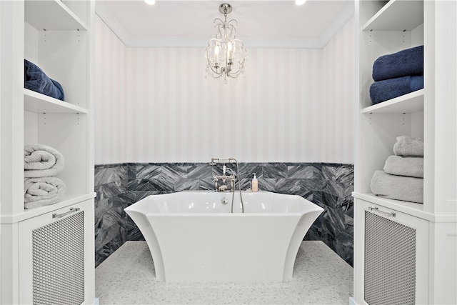 bathroom with a tub to relax in, tile walls, ornamental molding, and an inviting chandelier