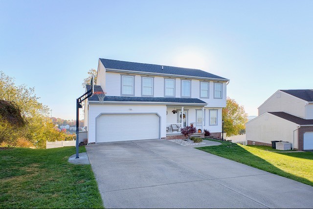 view of front facade featuring a garage, a front lawn, and central air condition unit