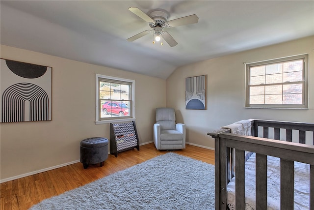 bedroom featuring vaulted ceiling, ceiling fan, a nursery area, and light hardwood / wood-style flooring