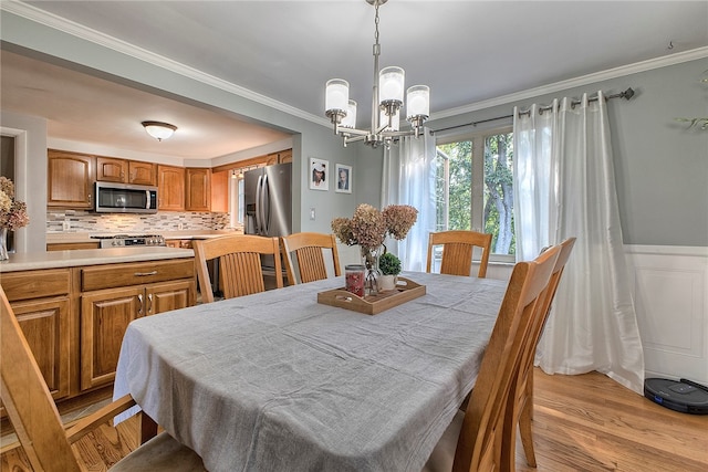 dining area featuring a notable chandelier, light wood-type flooring, and crown molding