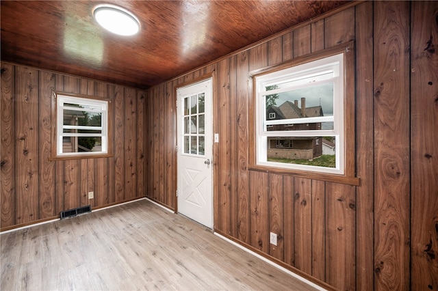 empty room featuring light wood-type flooring, wooden walls, and wooden ceiling