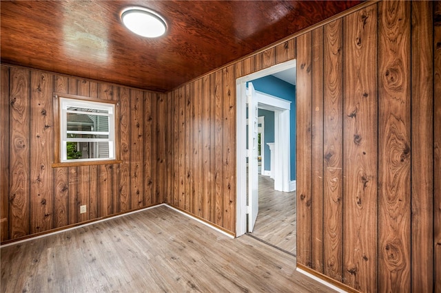 empty room featuring wood ceiling, wooden walls, and light hardwood / wood-style floors