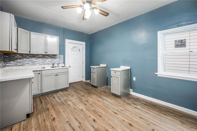 kitchen featuring light wood-type flooring, backsplash, sink, and ceiling fan