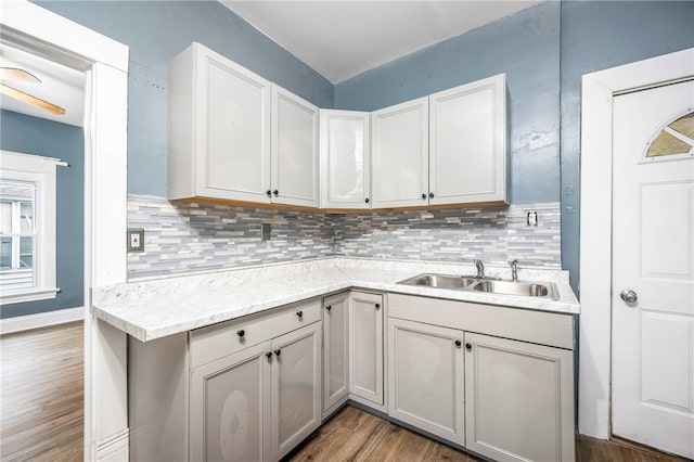 kitchen with decorative backsplash, white cabinets, hardwood / wood-style flooring, and sink