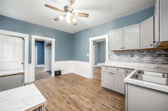 kitchen featuring ceiling fan, sink, tasteful backsplash, gray cabinetry, and light hardwood / wood-style floors