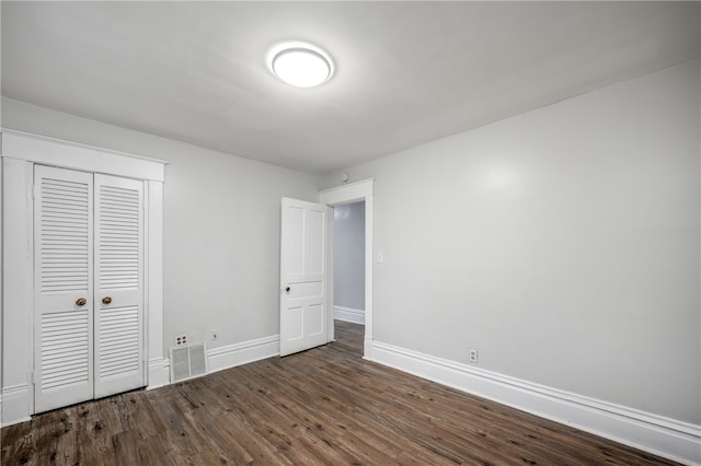 unfurnished bedroom featuring a closet and dark hardwood / wood-style floors