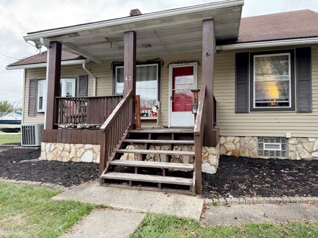 entrance to property featuring a porch and central air condition unit