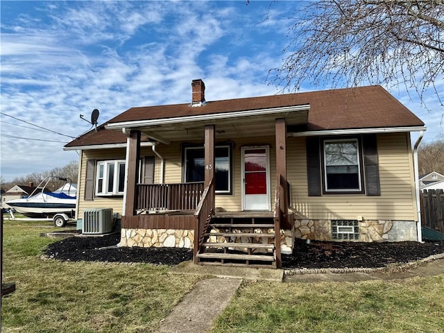 bungalow-style home with a front yard, central AC unit, and covered porch