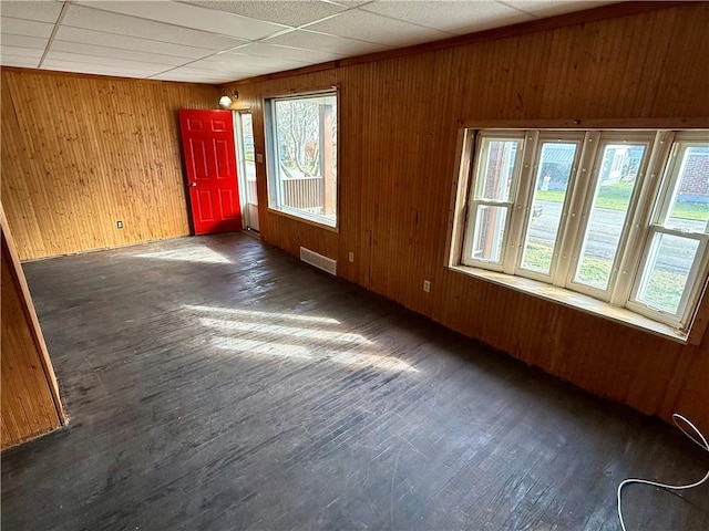 spare room featuring a paneled ceiling and wooden walls