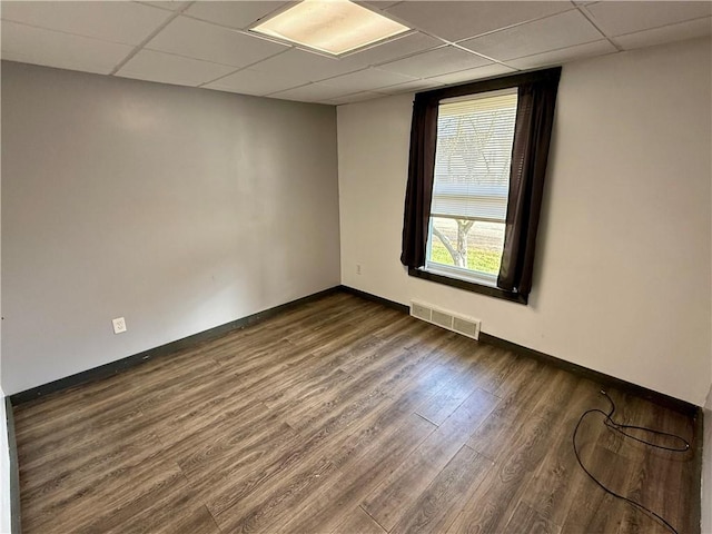 unfurnished room with a paneled ceiling and dark hardwood / wood-style floors