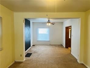 empty room featuring ceiling fan and carpet