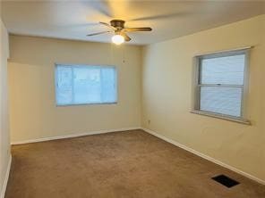 spare room featuring dark carpet and ceiling fan