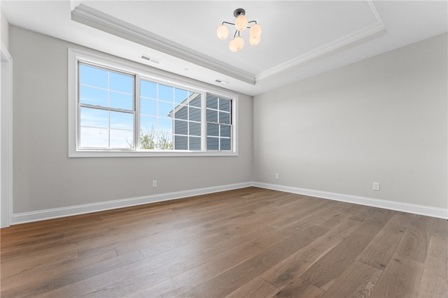 unfurnished room with a notable chandelier, a raised ceiling, and hardwood / wood-style flooring