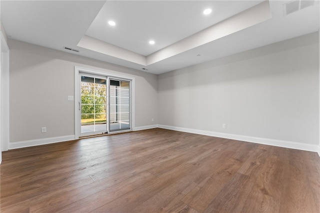 spare room with a raised ceiling and dark wood-type flooring