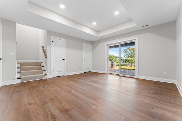 unfurnished living room featuring a tray ceiling and hardwood / wood-style flooring