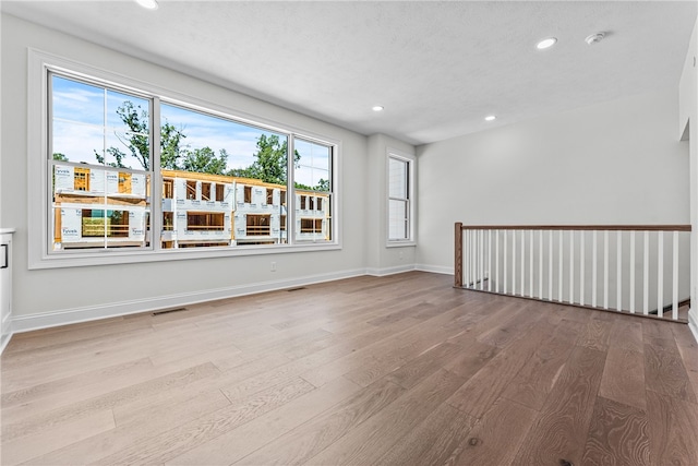 spare room with light wood-type flooring and a textured ceiling