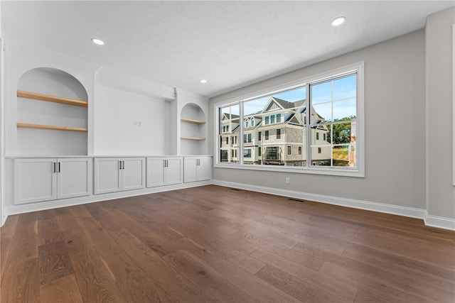 unfurnished living room with dark hardwood / wood-style floors and built in features