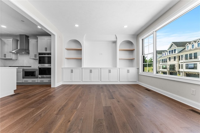 unfurnished living room with built in shelves and dark hardwood / wood-style floors