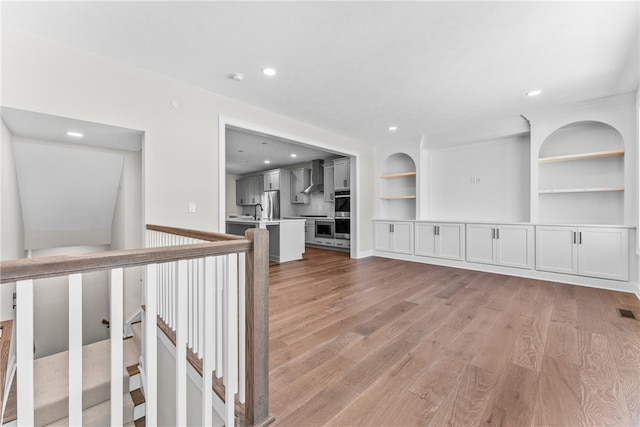 interior space featuring built in shelves, sink, and light hardwood / wood-style floors