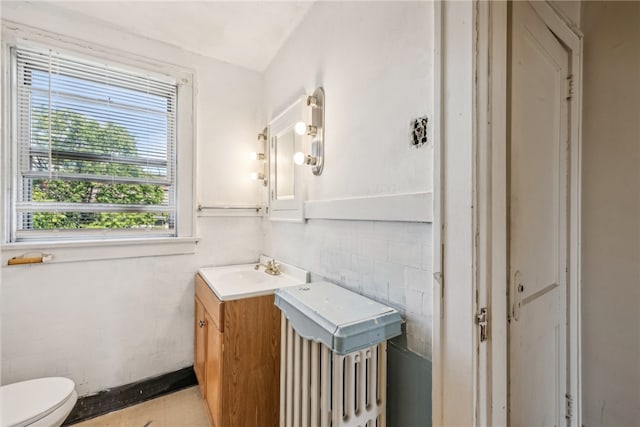 bathroom with vanity, toilet, and tile walls