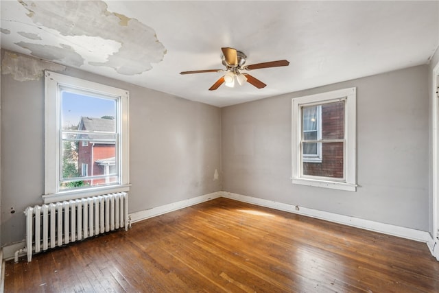 unfurnished room featuring radiator heating unit, ceiling fan, and dark hardwood / wood-style floors