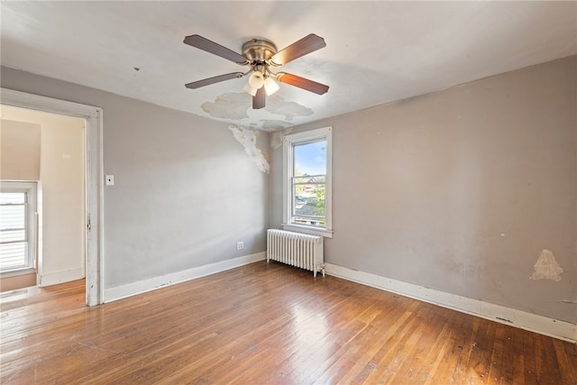 empty room with radiator heating unit, hardwood / wood-style floors, and ceiling fan