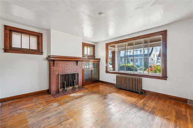 unfurnished living room featuring radiator, a fireplace, and hardwood / wood-style floors