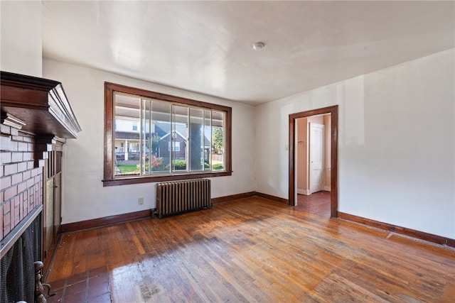 unfurnished living room with radiator, a fireplace, and dark hardwood / wood-style floors