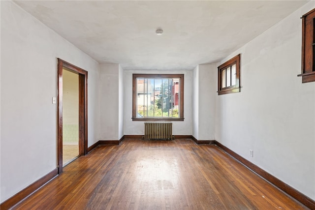 spare room with dark wood-type flooring and radiator heating unit