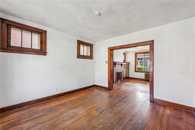 unfurnished room featuring radiator, dark hardwood / wood-style flooring, and a fireplace