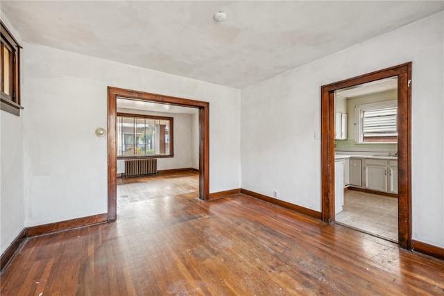 empty room with hardwood / wood-style floors, a healthy amount of sunlight, and radiator