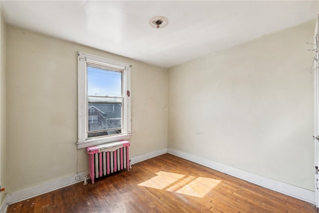 empty room featuring radiator heating unit and dark hardwood / wood-style floors