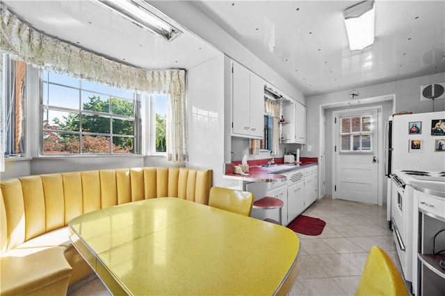 kitchen with white cabinetry, electric stove, light tile patterned floors, and sink