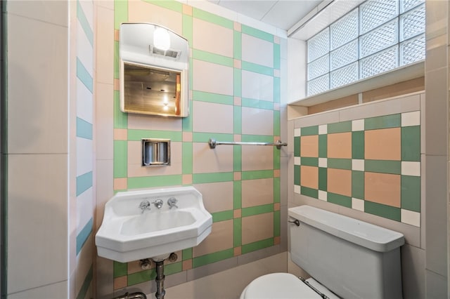 bathroom with sink, tile walls, and toilet