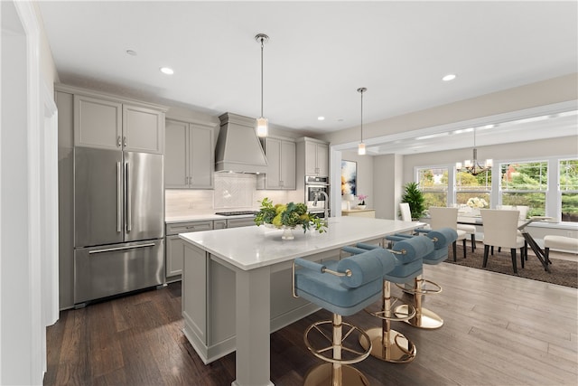 kitchen with gray cabinets, appliances with stainless steel finishes, custom range hood, and dark hardwood / wood-style flooring